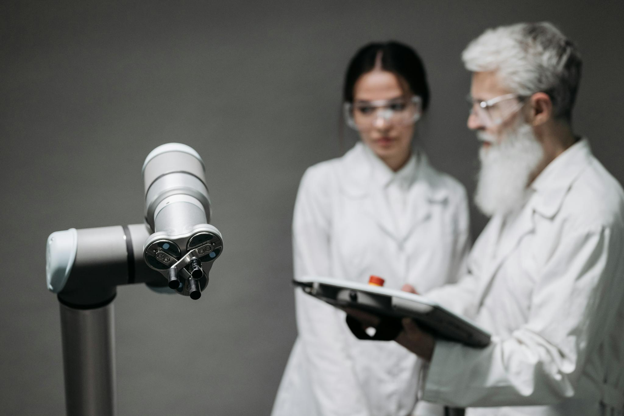 Researchers in lab coats analyze robotic equipment for technological advancement.